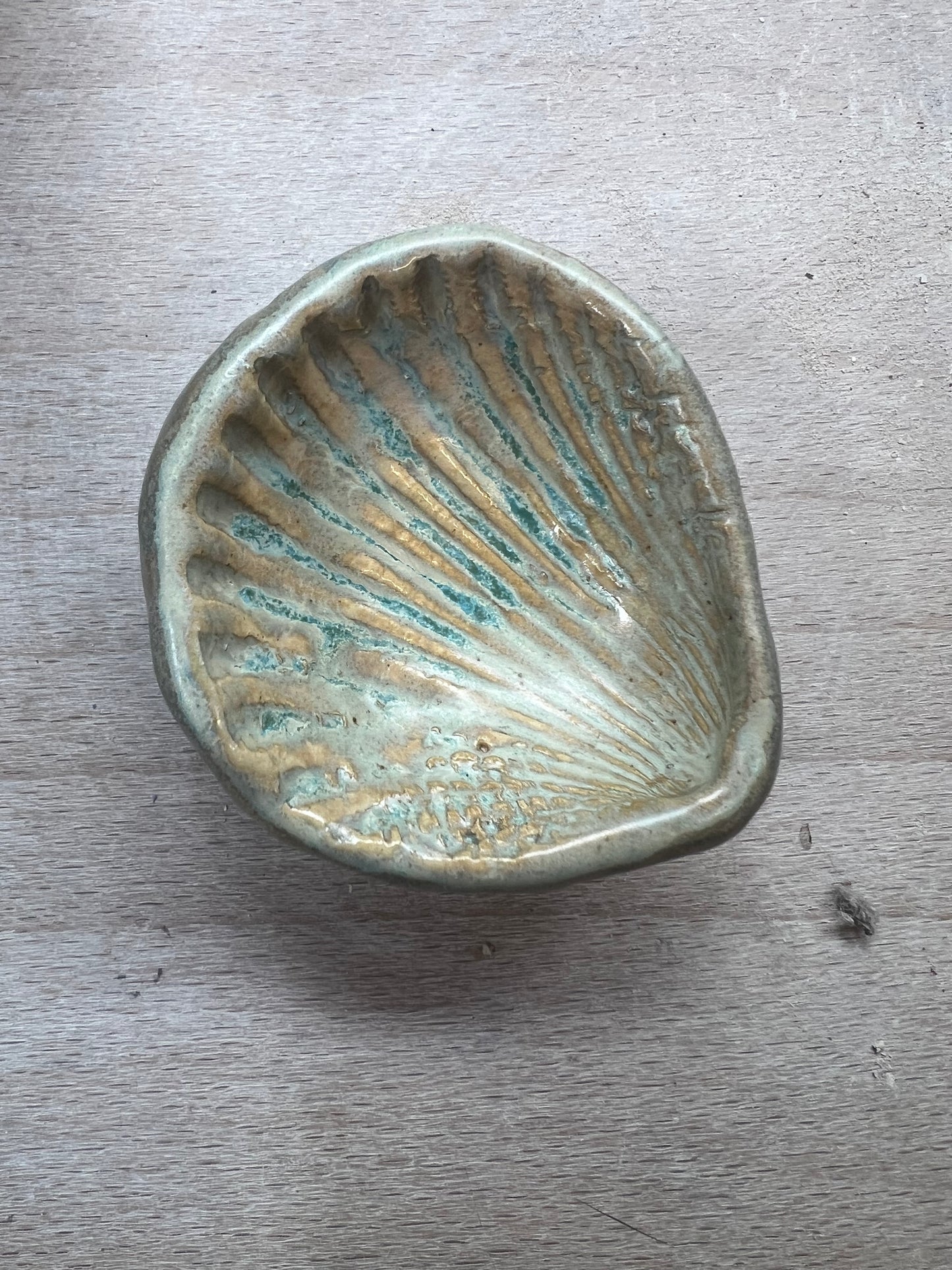 Ceramic shell dish with ribbed texture on a wooden surface