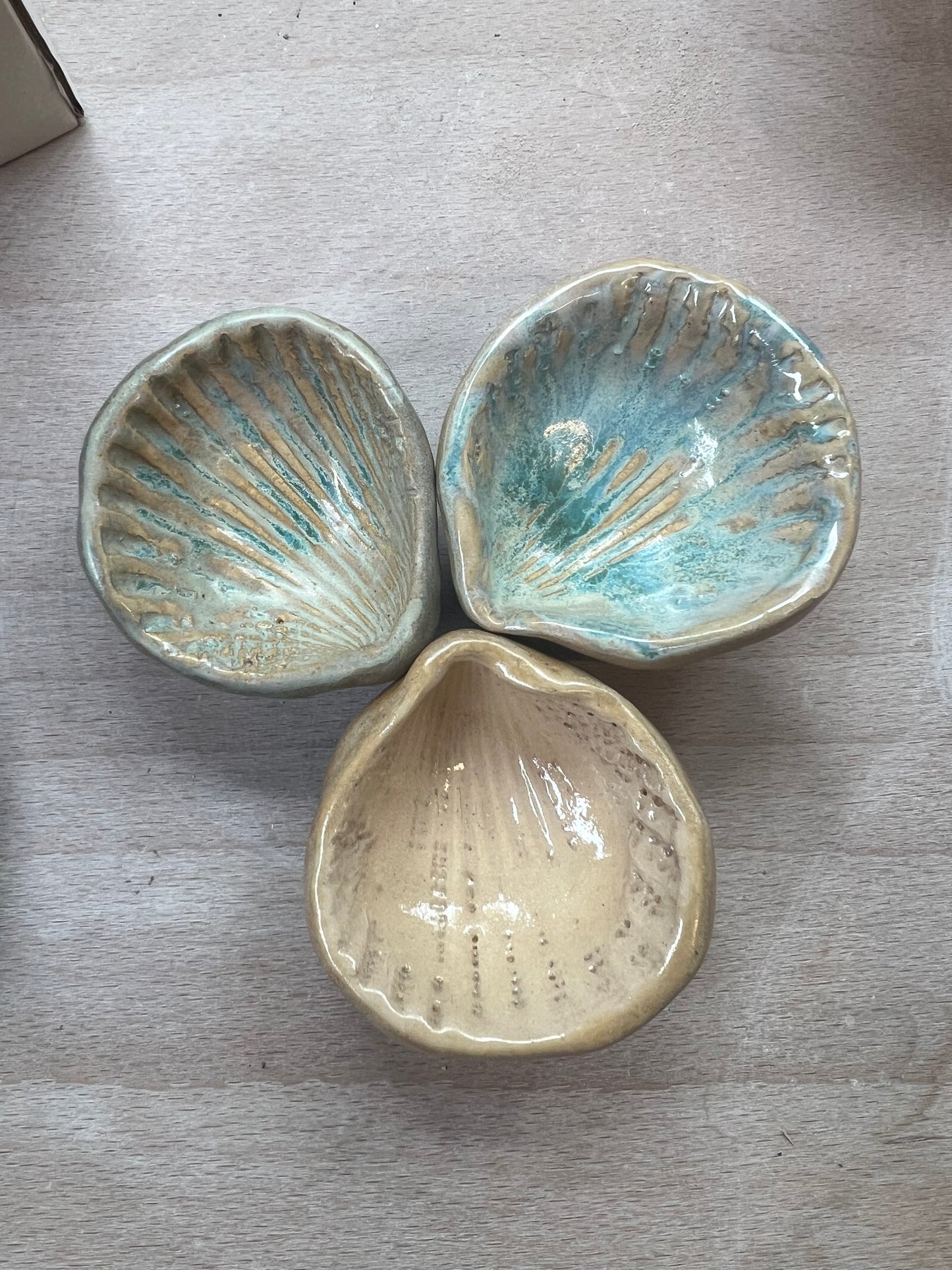 Three ceramic shell-shaped dishes on a wooden surface