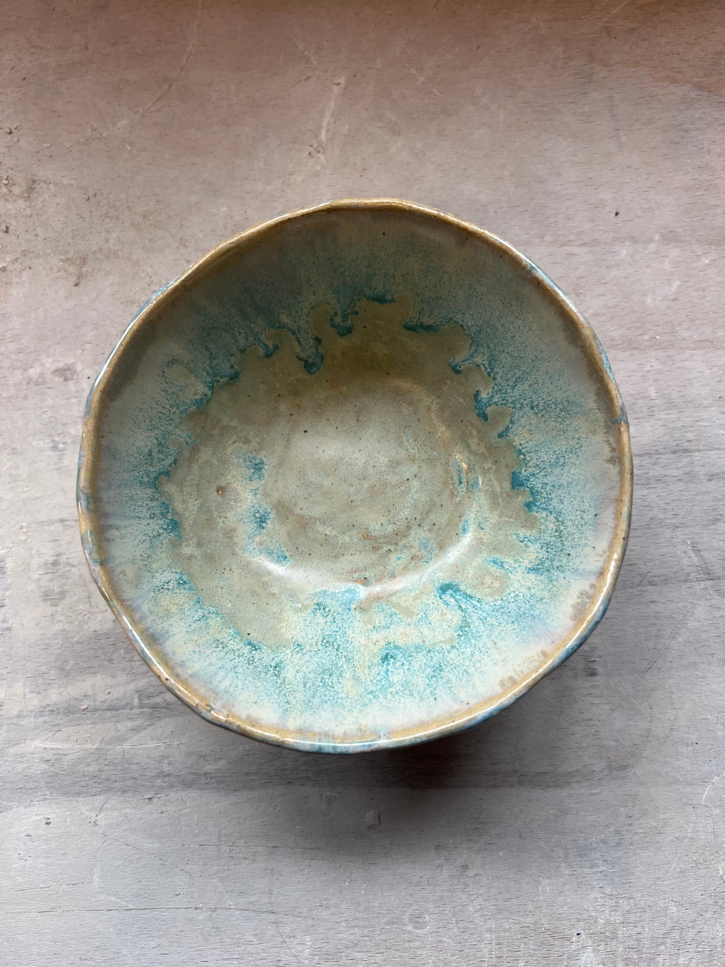 Ceramic bowl with beautiful blue and green glaze on wooden surface
