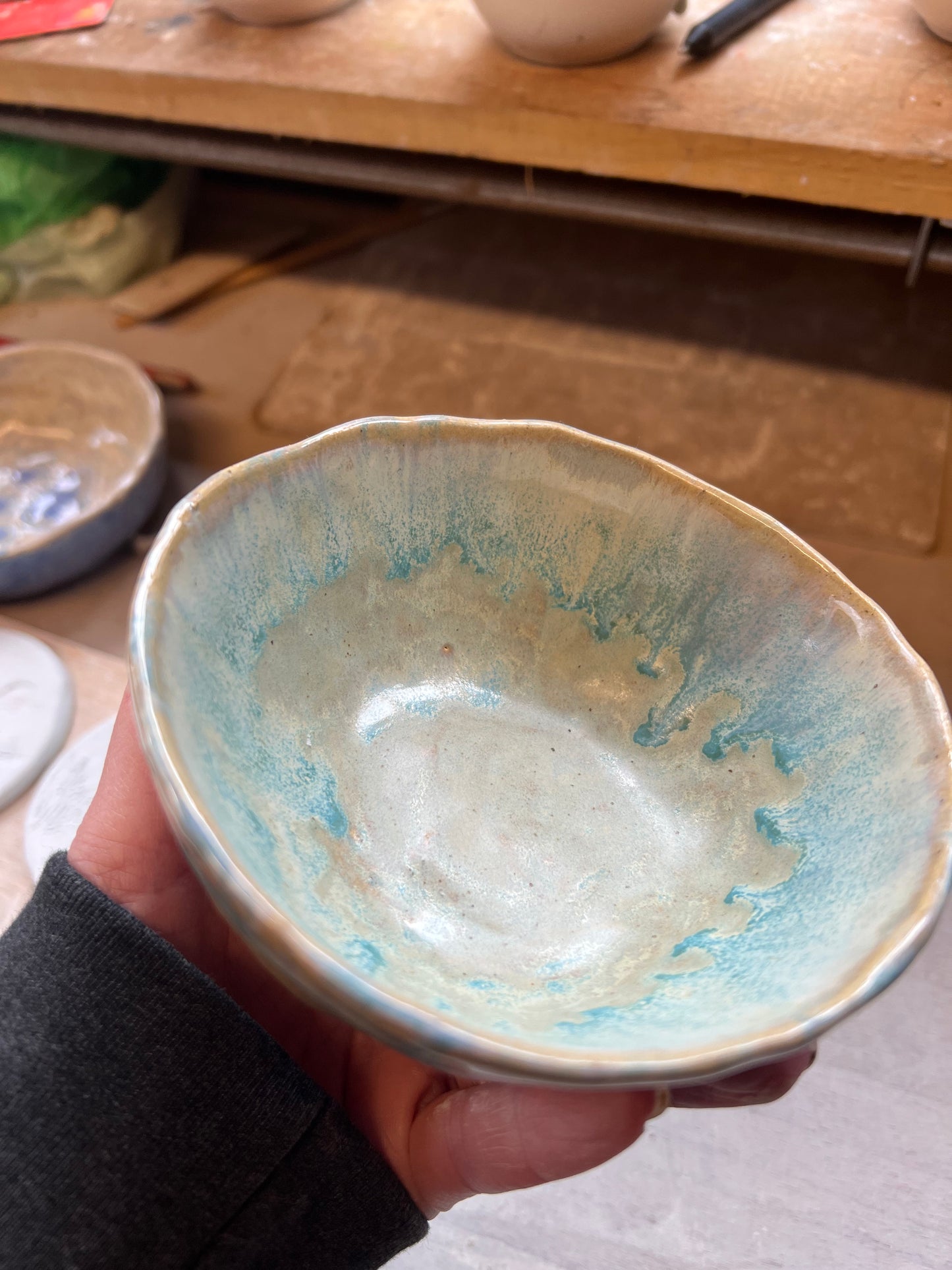 Hand holding a ceramic bowl with blue and green glaze