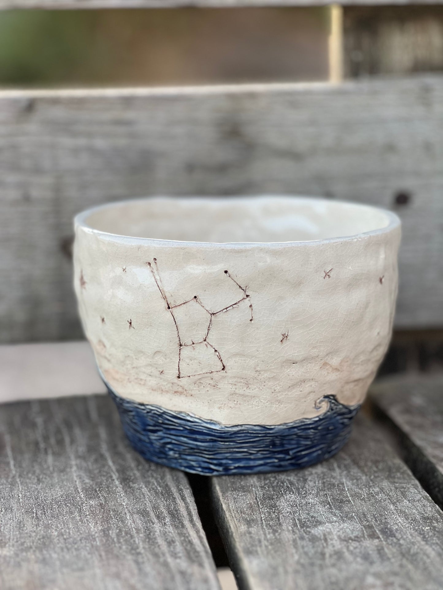 Ceramic pot with star constellation design on a wooden surface