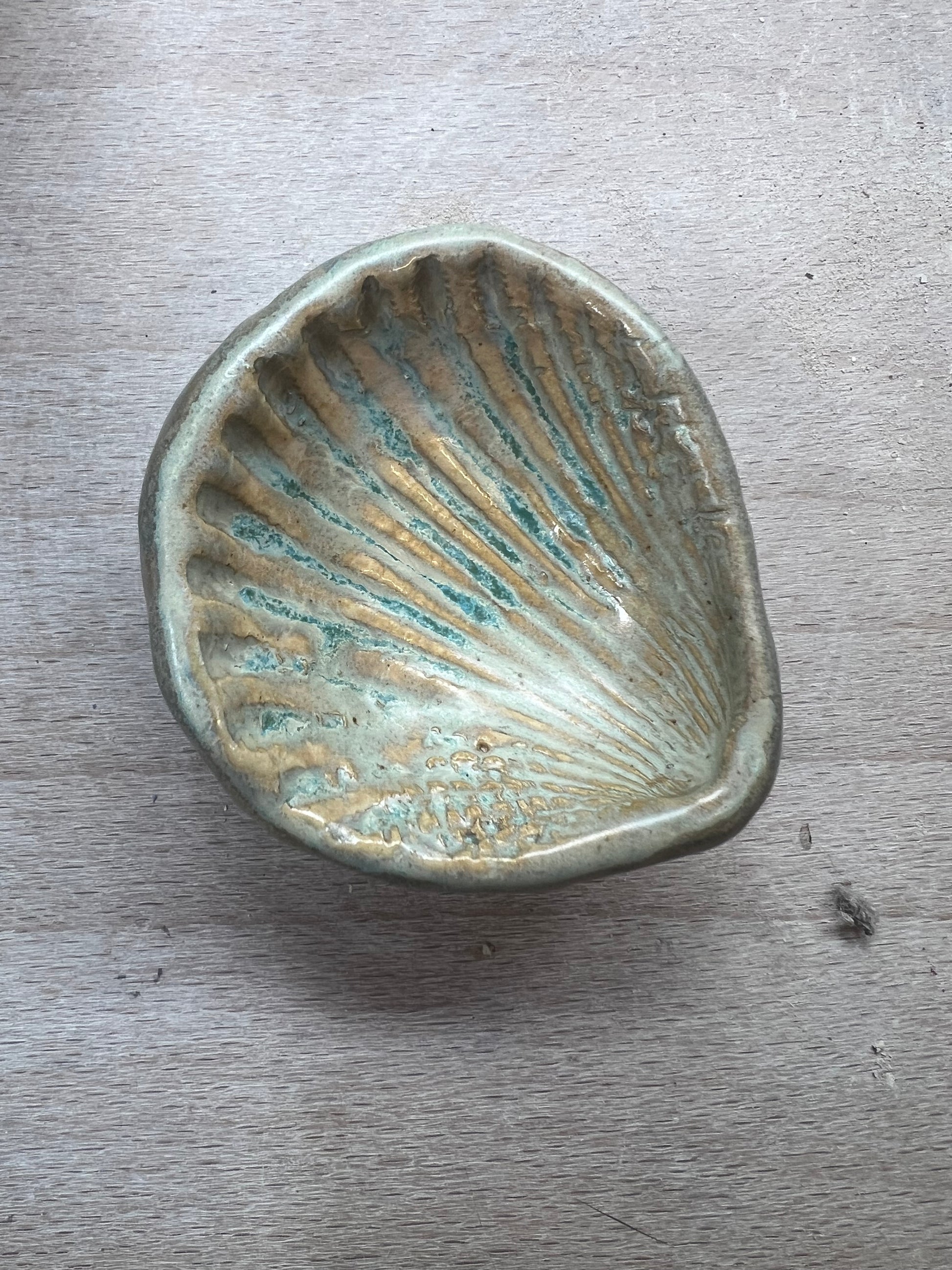 Ceramic shell dish with ribbed texture on a wooden surface