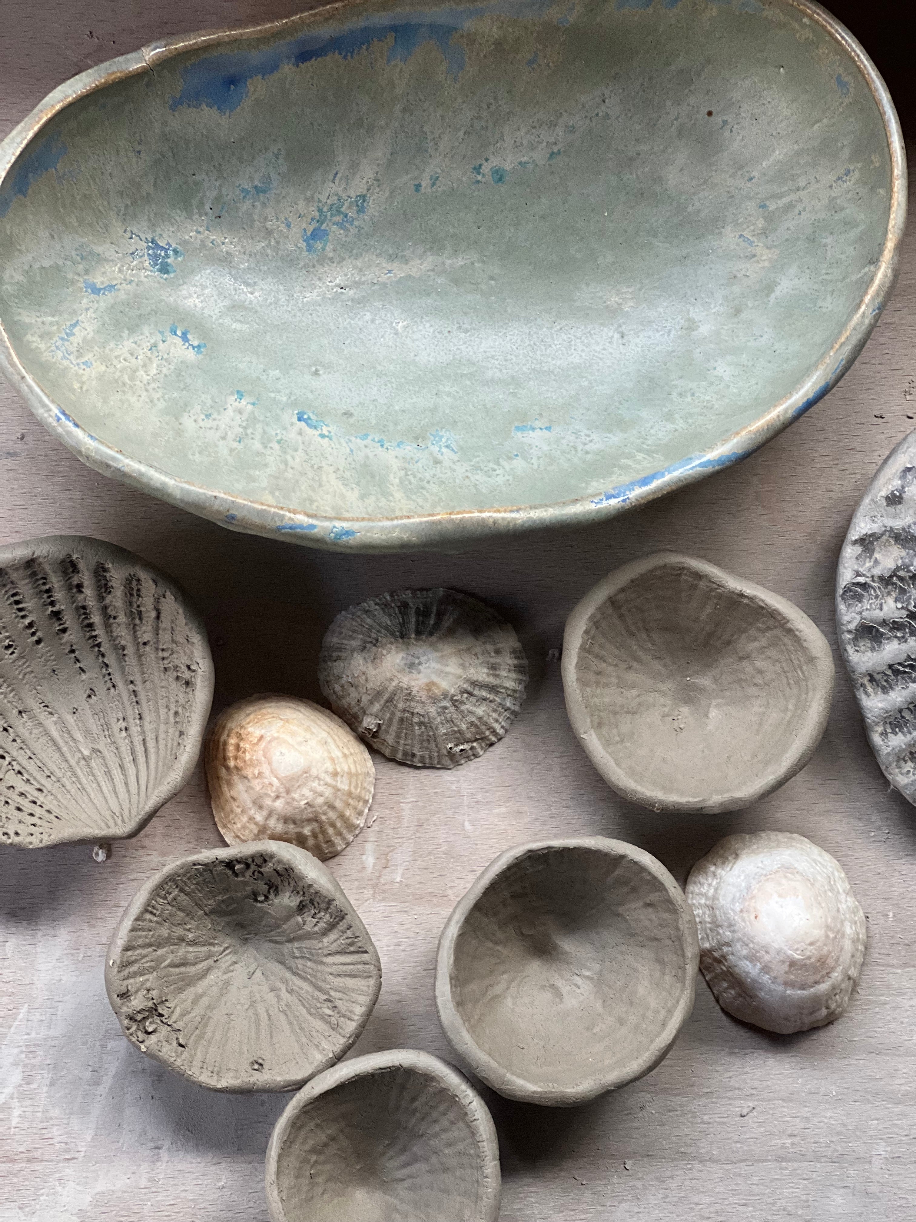 Collection of ceramic bowls and shells on a textured surface