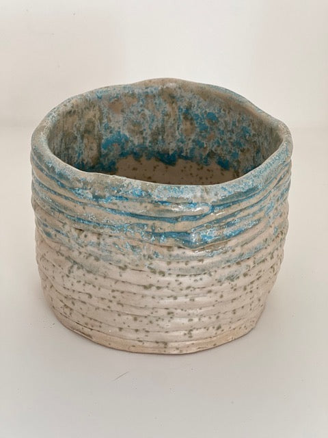Ceramic pot with blue glaze on a speckled background